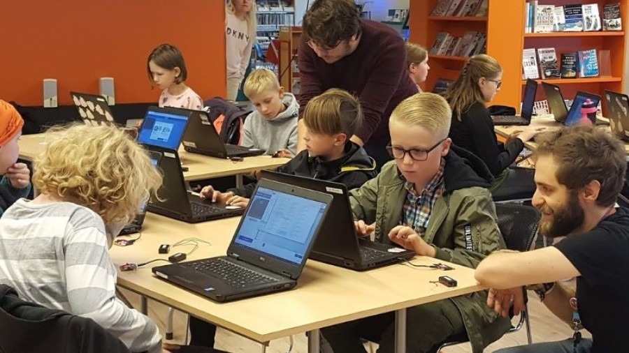 Teacher instructing a blond boy with a computer